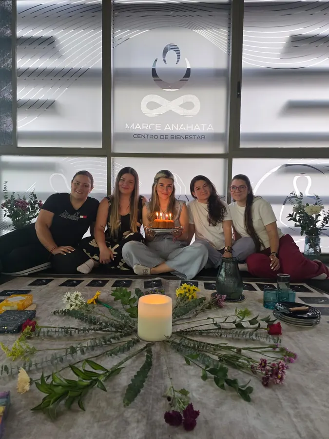 Birthday woman holding her cake, surrounded by her guests at the end of the ritual